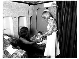
Cabin service in SAA Boeing 747 interior, hostess with baby in bassinet.
