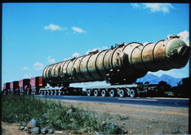 Heavy cylindrical vessel drawn by four SAR International Pacific trucks.