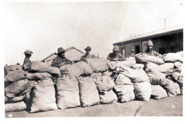 Workers with stack of bags at railway station.