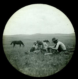 Men mending clothes in veld.