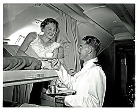 
SAA Douglas DC-7B interior. Lady served tea in sleeper bunk. Steward.
