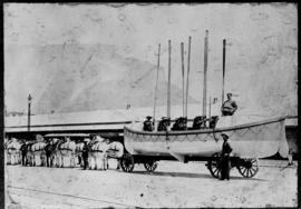 Rowing boat on trailer drawn by white horses.