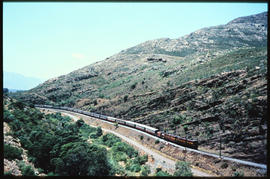 SAR Class 5E with passenger train travelling through narrow kloof.
