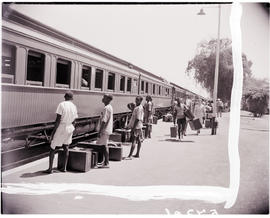 
Passengers with luggage boarding train.
