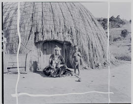 
Woman and child in front of hut.
