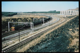 Multiple train tracks next to grain elevator.