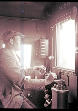 
Driver at controls in the cab of SAR 4M1 suburban electric locomotive. Note five buttons on cont...