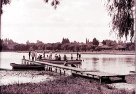 Female anglers with boat at jetty on wide river.