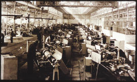 Factory interior with rows of workmen.