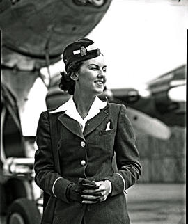 
SAA Lockheed Constellation hostess Miss Manchip standing next to engine.
