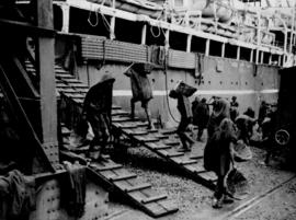 Dock workers loading coal onto ship.