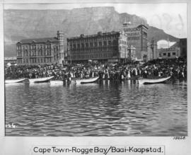 Cape Town. Large crowd and boats on beach at Rogge Bay with city in the  distance.