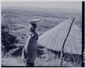 Tzaneen district, 1951. Woman carrying basket at hut in Duiwelskloof.