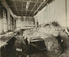 Interior of room with stripped ceiling with debris on floor.