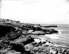Hermanus, 1948. Rugged coastline with village in the distance.