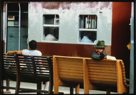Passengers waiting on bench at station platform.