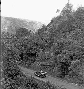 George. Motor car on mountain road in forest.
