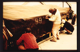 Fixing tarpaulin onto railway wagon.