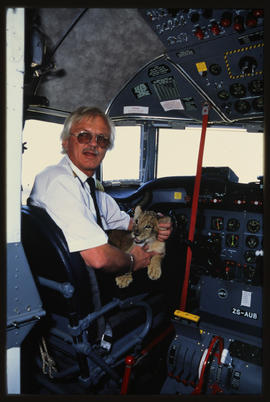 Pilot, Captain Flippie Vermeulen, with lion cub in the cockpit of SAA Douglas DC-4 ZS-AUB 'Outeni...