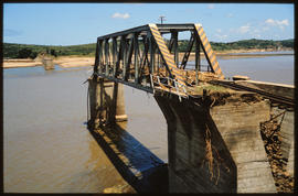Damaged bridge over wide river.