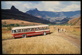 
SAR Leyland Olympic tour bus with passengers at roadside stop with Amphitheatre in the distance.
