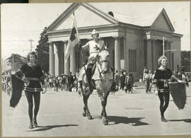 Street procession led by man on horseback.
