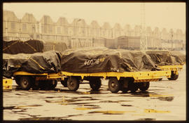 Truck and trailer loads under tarpaulins in the rain.