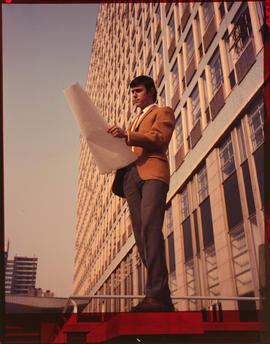 Architect checking drawing in front of tall building.