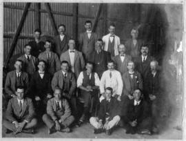 Group of men posing in corrugated iron shed.