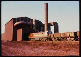 SAR Class 34-000 with goods train at large industrial plant.