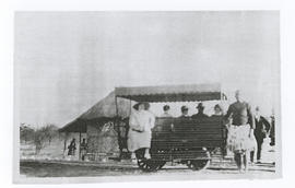 Small, primitive railway coach with passengers.