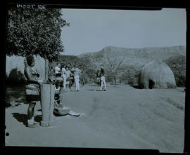 Natal, 1968. Zulu women grinding maize with visitors in the distance.