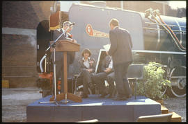 Johannesburg, July 1989. Podium with speaker next to SAR Class 25NC No 3476 'Griet' with winged s...