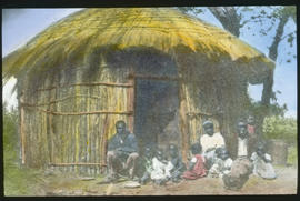 Black family in front of traditional hut.