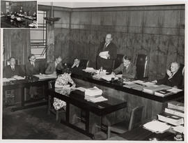Minister Paul Sauer addressing a meeting. The chairs in the room carry the logo of the Automobile...