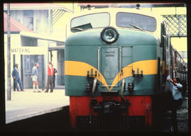 Mafeking, 1980. RR Class diesel locomotive with passenger train at station platform.