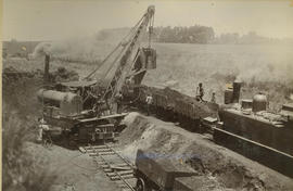 Rail excavator removing embankment next to double railway track.
