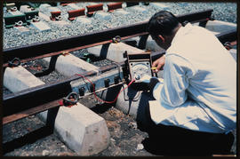 Technician making measurements at bolted rail connection.