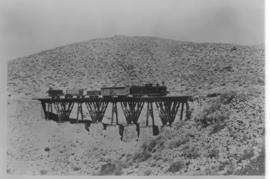 Okiep - Port Nolloth narrow gauge railway. Train on bridge supported by timber columns on stone p...