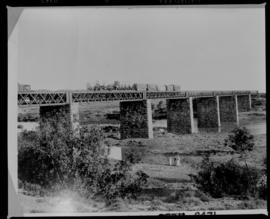 Modder River, 1896. Goods train on bridge over the Modder River with Cape carts on train.