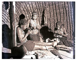 Natal, 1951. Three Zulu women threading beads inside hut.