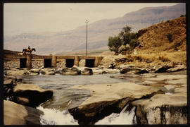 Drakensberg, October 1976. Horseman crossing concrete bridge over stream near Cathedral Peak. [D ...
