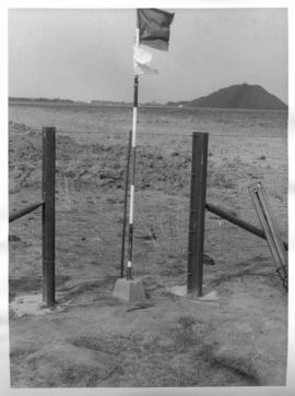 Trigonometric beacon marked with a flag, with mine dump in the distance.
