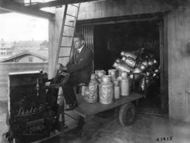Man in suit loading milk cans