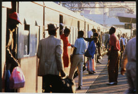 Passengers next to train on station platform.