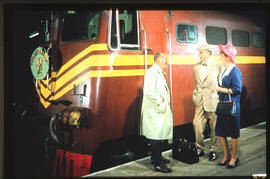 Passengers speaking to driver of Trans-Karoo passenger train on station platform.