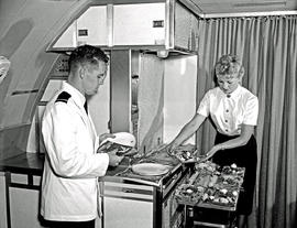 
SAA Boeing 707 interior. Meal preparation in galley. Steward and hostess.
