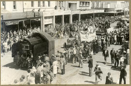 Procession of floats in business street.