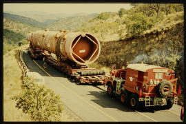 Heavy cylindrical vessel drawn by SAR International Pacific truck on open road.