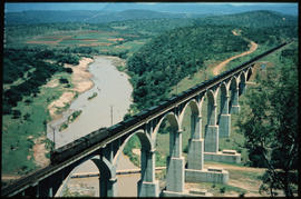 Coal train on high concrete arch bridge.